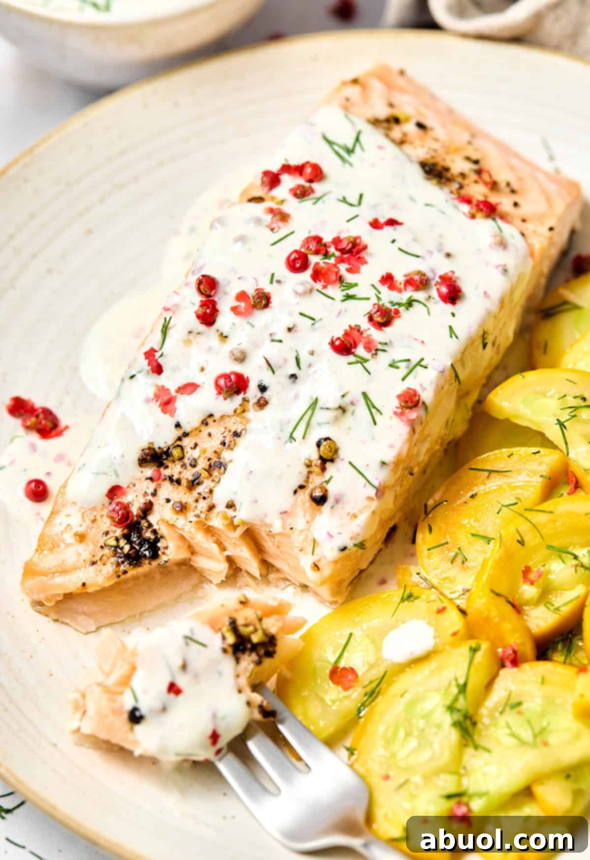 Plate with Oven Roasted Salmon with Pink Peppercorn Sauce and yellow squash on the side. A few bites have been taken out of the fish to show the flaky inside. 