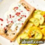 Roasted salmon with pink peppercorn sauce and yellow squash on plate