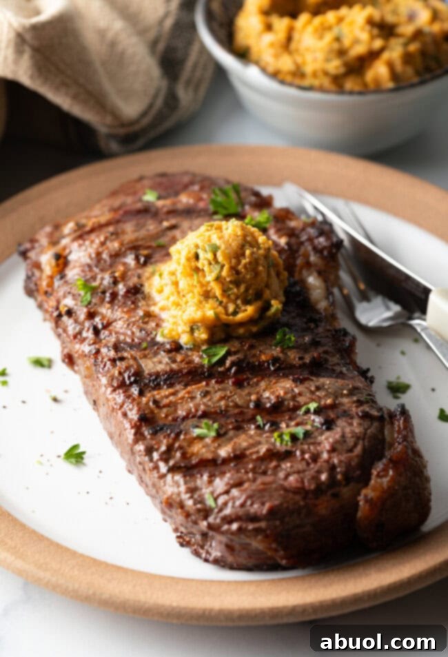 Grilled steak on a white plate with scoop of spiced compound cowboy butter on top.