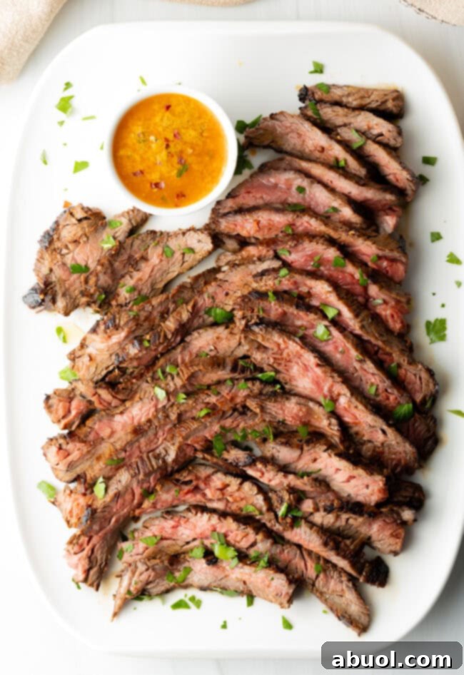 Top down slices of tender cooked beef on a white platter. Ramekin of melted butter on the side of the plate.