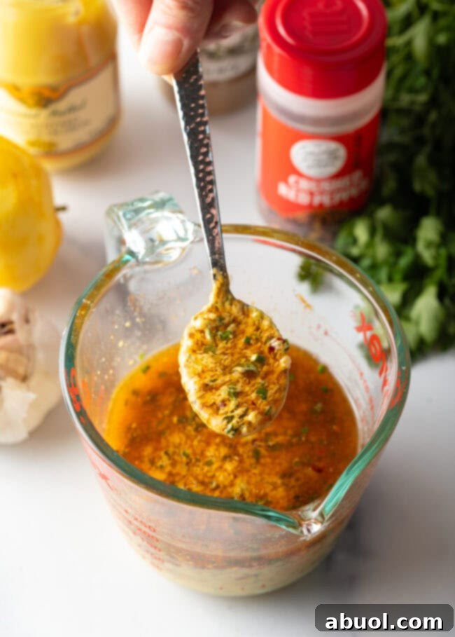 Hand with metal spoon, showing spoonful of melted spiced butter to camera.