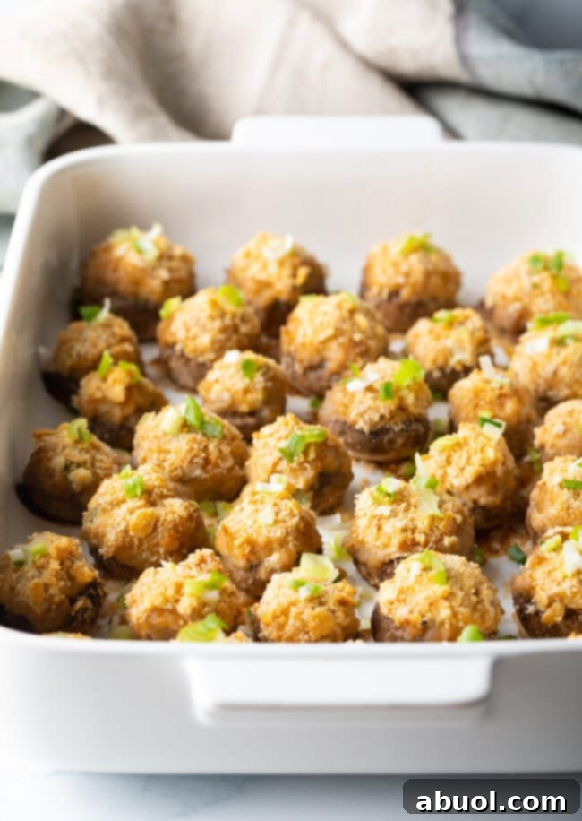 Two dozen crab stuffed mushrooms with ritz crackers in a white baking dish.