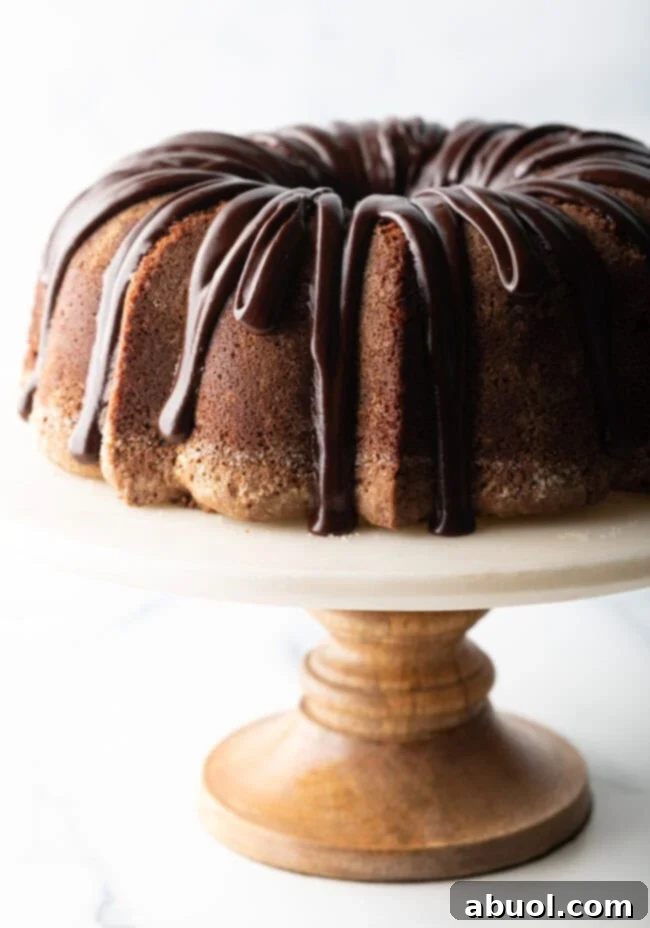 Chocolate Glaze for Pound Cake - Chocolate sour cream bundt cake with a thick chocolate glaze drizzled on top. The cake is on a white stand.