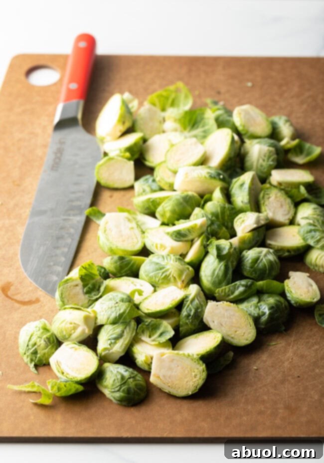 Cleaned and halved brussel sprouts on a brown cutting board, with a large knife.