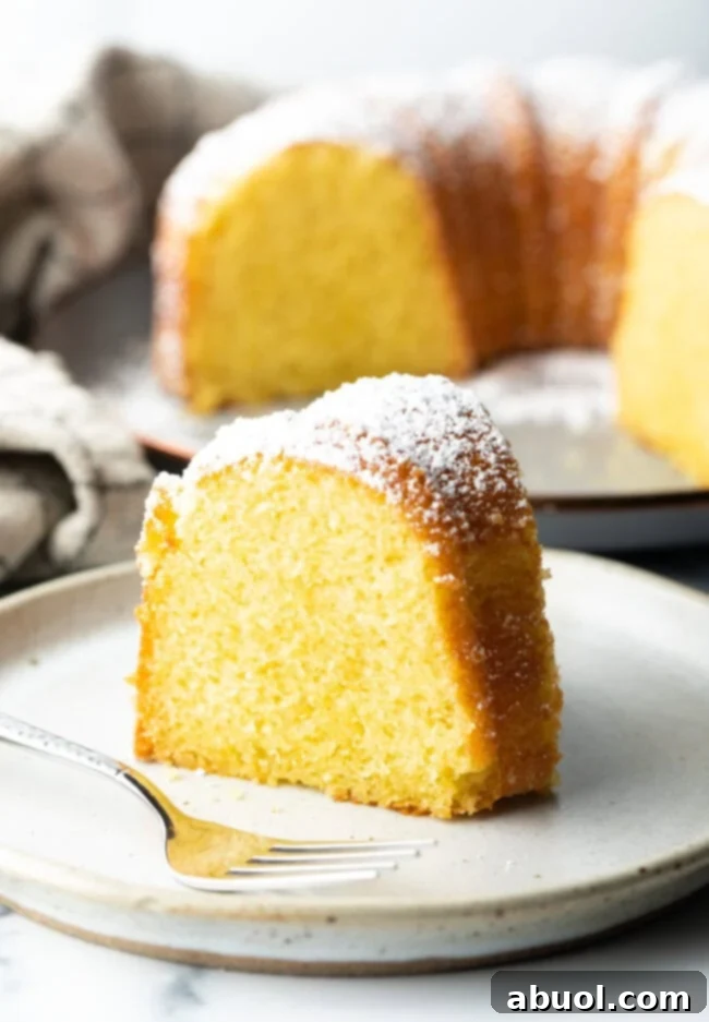 Golden Lemon Olive Oil Cake 2 A perfectly baked slice of yellow lemon olive oil cake resting on a pristine white plate, showcasing its moist crumb.