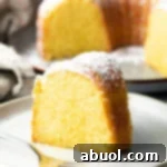 A tempting slice of yellow cake on a white plate, showcasing the moist interior.