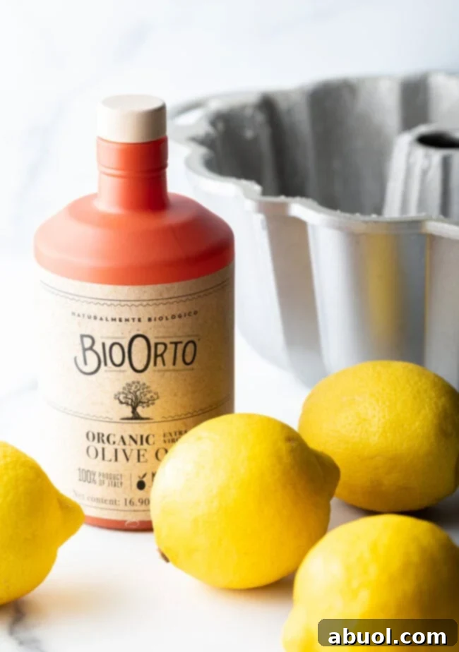 Golden Lemon Olive Oil Cake 5 Recipe ingredients featuring a bottle of premium olive oil and four fresh, vibrant lemons, ready for baking.