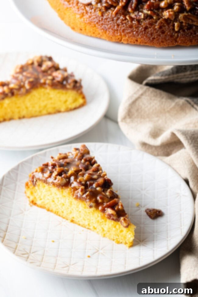 Two exquisite slices of Pecan Upside Down Cake, one in the foreground perfectly plated, and another blurred in the background, inviting guests to indulge.