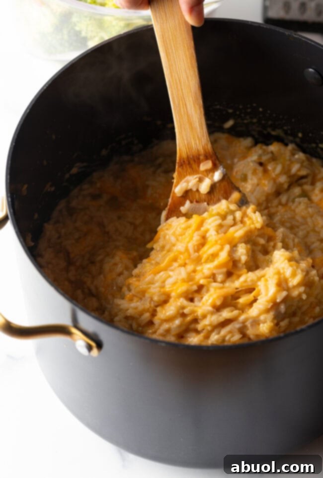 Wooden spoon stirring cheese and rice.