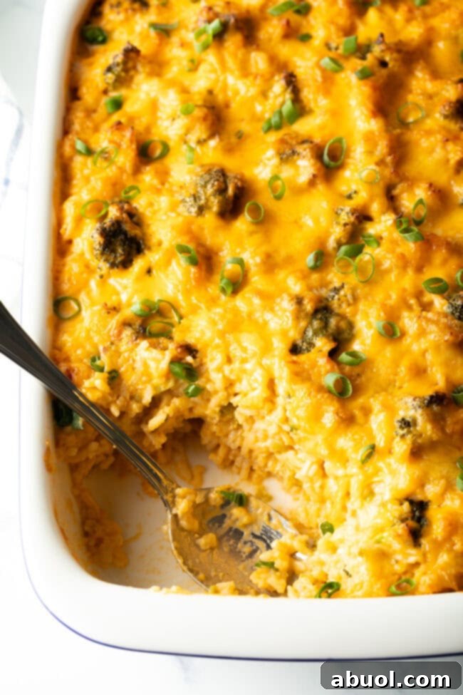 Easy broccoli rice casserole in a white baking dish. A metal spoon is scooping a portion from the dish.