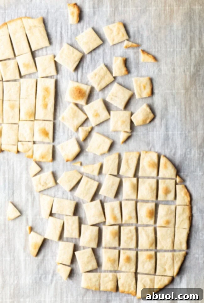 Two pieces of unleavened bread laying on a gray background. Each large oval of bread has been sliced into small squares.