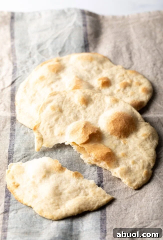 Two pieces of unleavened bread laying on a gray background. One bread has been split into two pieces.