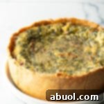 Baked veggie quiche with a deep dish crush on a white round plate.