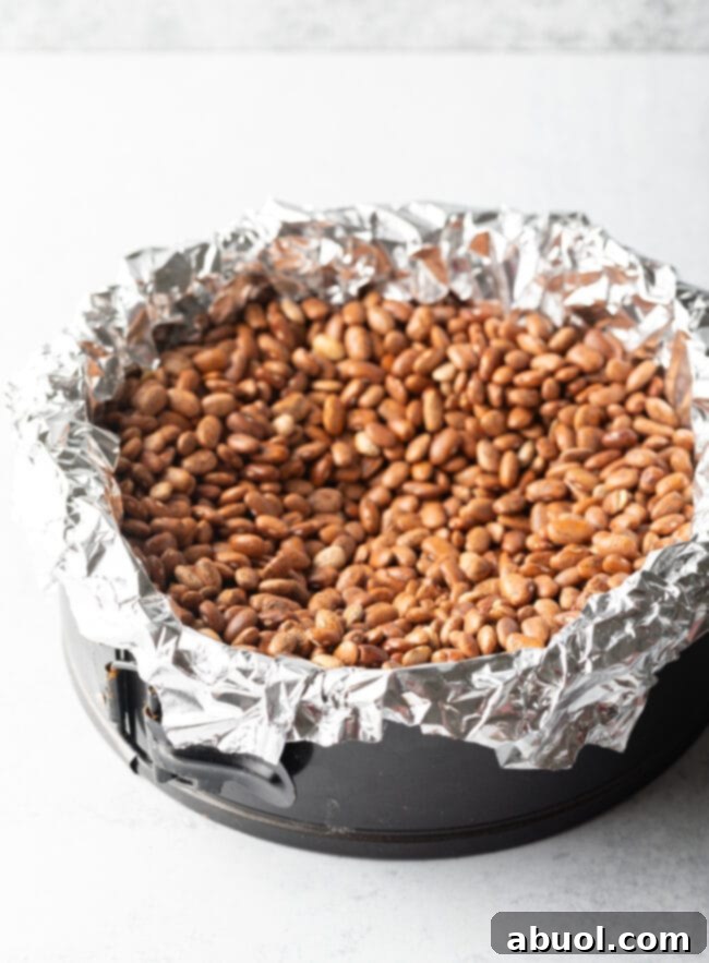 Blind baking the pie crust in the springform pan by lining with aluminum foil and filling with dry kidney beans.