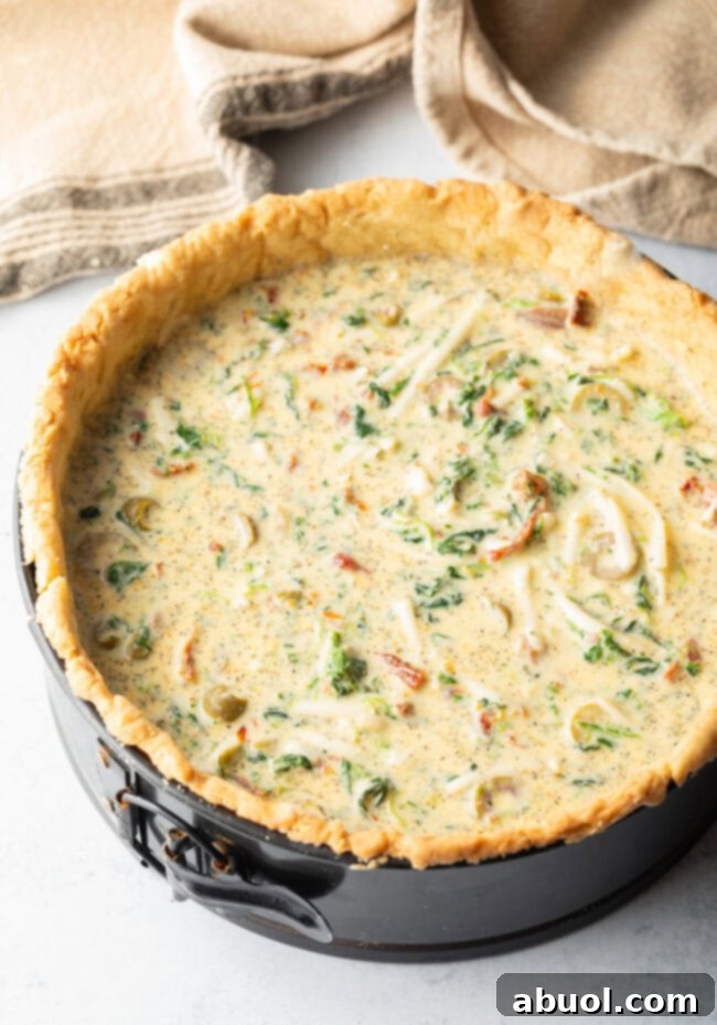 Top down view unbaked egg mixture in a deep dish pie crust within a springform pan.