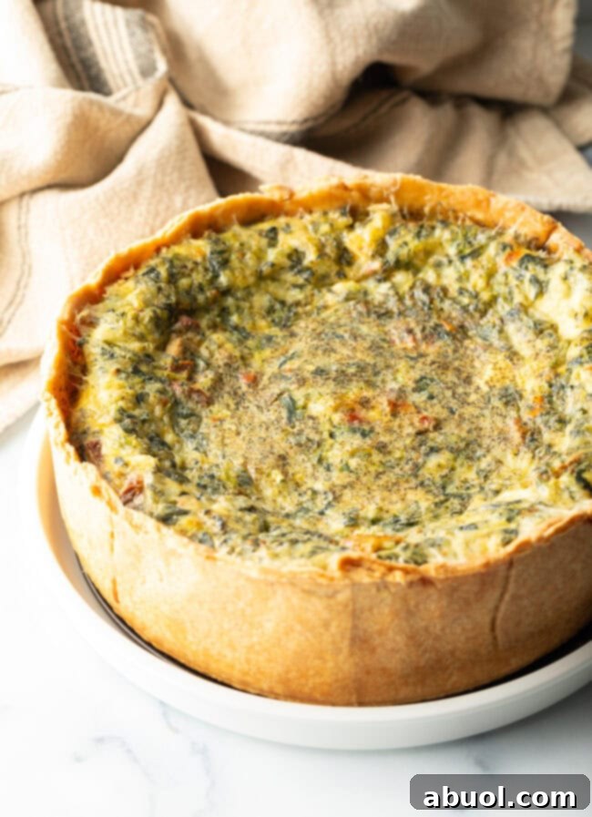 Baked veggie quiche with a deep dish crush on a white round plate.
