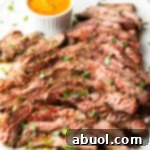 Thin slices of Bavette steak on a white serving platter with a ramekin of cowboy butter to the side.