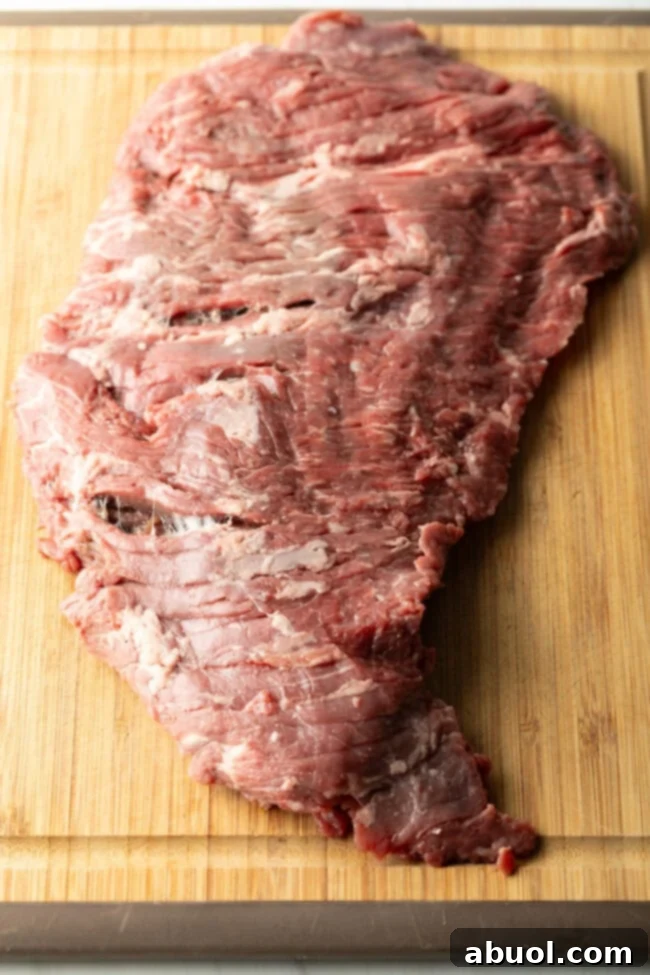 Large piece of raw beef on a wooden cutting board.