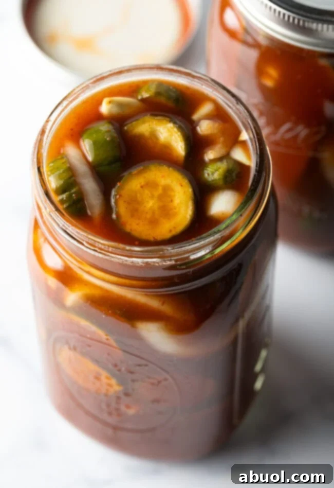 Two glass jars filled with cucumber slices and chamoy seasonings.