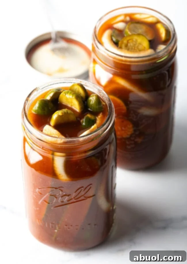Two glass jars filled with cucumber slices and chamoy seasonings.