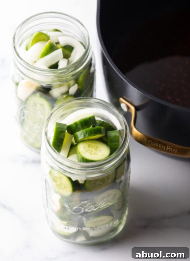 Cucumbers sliced into discs and filled into two large glass jars.