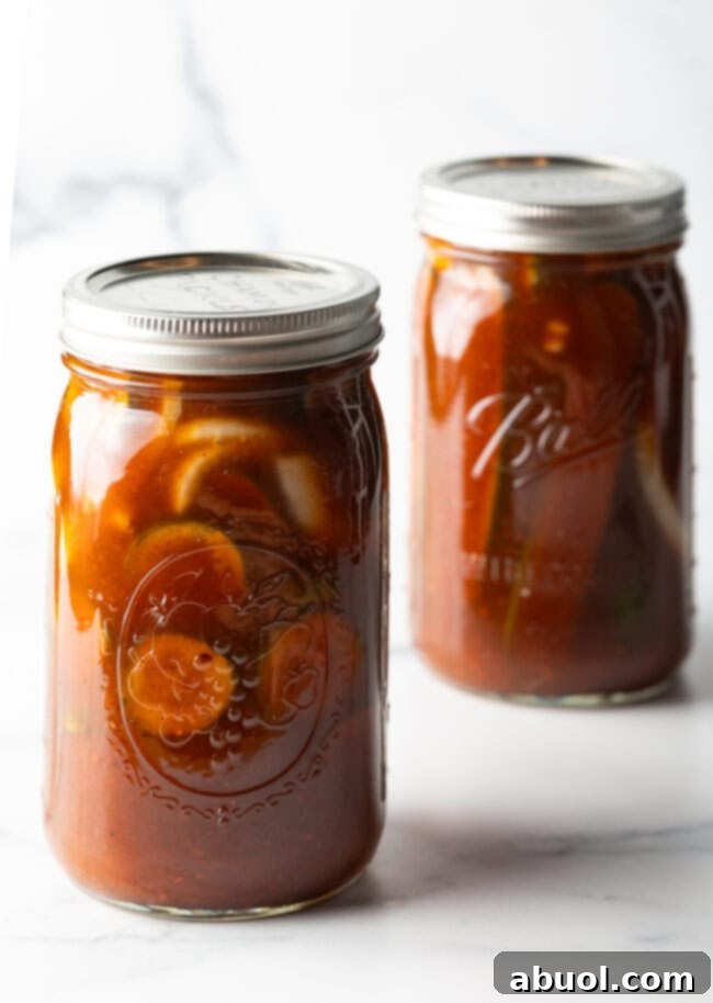 Two glass jars filled with cucumber slices and chamoy seasonings.
