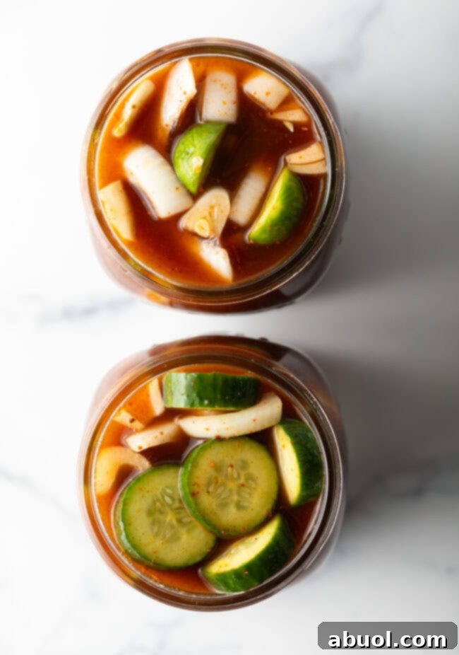 Two glass jars filled with cucumber slices and chamoy seasonings.