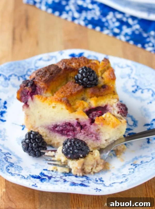 Slice of bread pudding with blackberries with a fork taking a bite. 