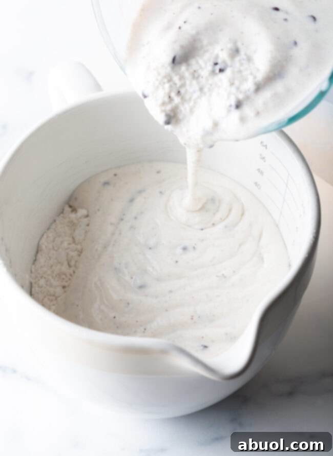Easy 3-Ingredient Ice Cream Bread 7 Adding melted ice cream to a white mixing bowl with flour.