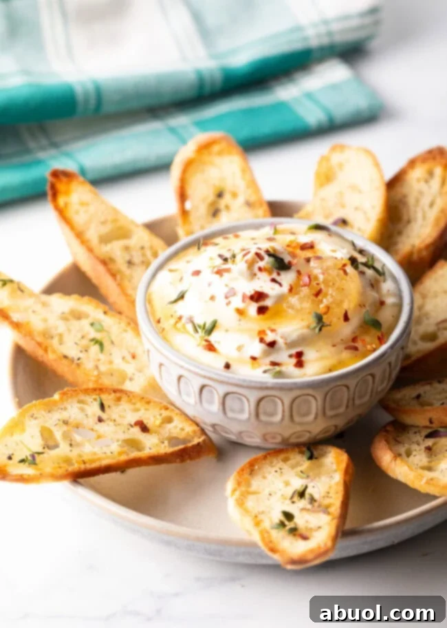 A vibrant display of whipped ricotta dip served in a white bowl, elegantly surrounded by toasted baguette slices, ready for a gathering.