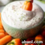 Mini orange pepper dipping into a small green bowl of white cottage cheese dip.