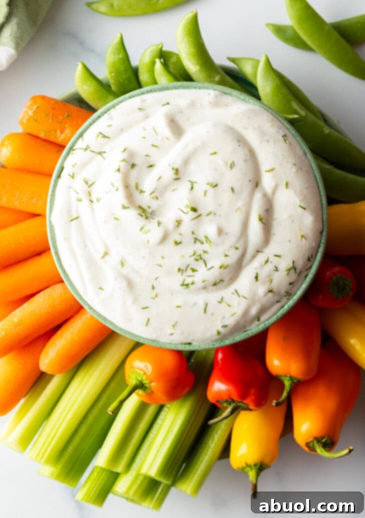 Bowl of cottage cheese dip surrounded by a sunburst of fresh veggies like carrots, mini bell peppers, celery, and green pepper slices.