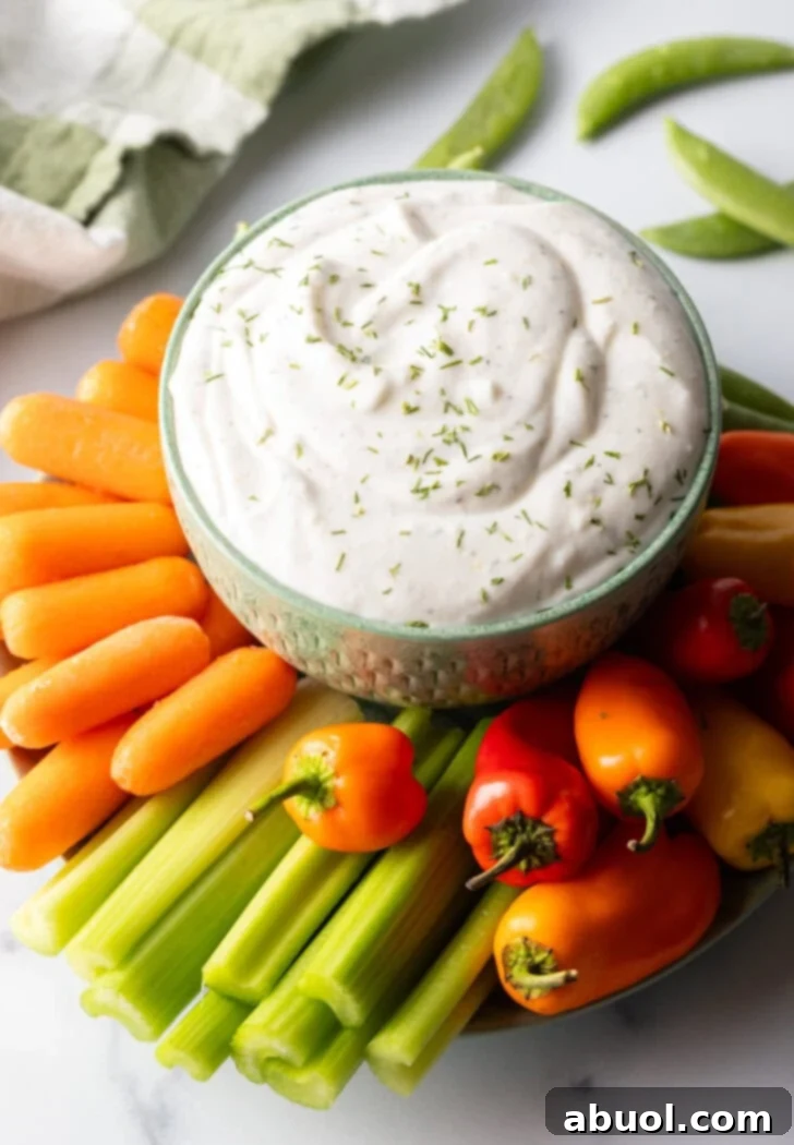 Bowl of cottage cheese dip surrounded by a sunburst of fresh veggies like carrots, mini bell peppers, celery, and green pepper slices.