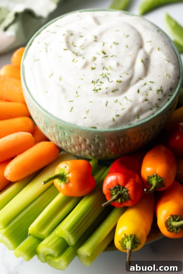 Bowl of cottage cheese dip surrounded by a sunburst of fresh veggies like carrots, mini bell peppers, celery, and green pepper slices.