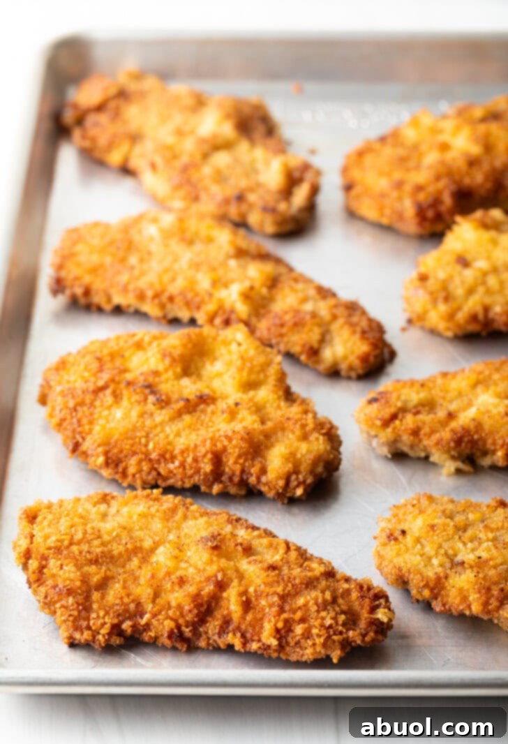 8 pieces of fried breaded veal on a baking sheet.