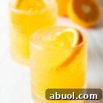 Ultimate Orange Crush Cocktail 13 Two orange crush cocktails in glasses, each garnished with a slice of orange. There are fresh oranges and lemons around the glasses.