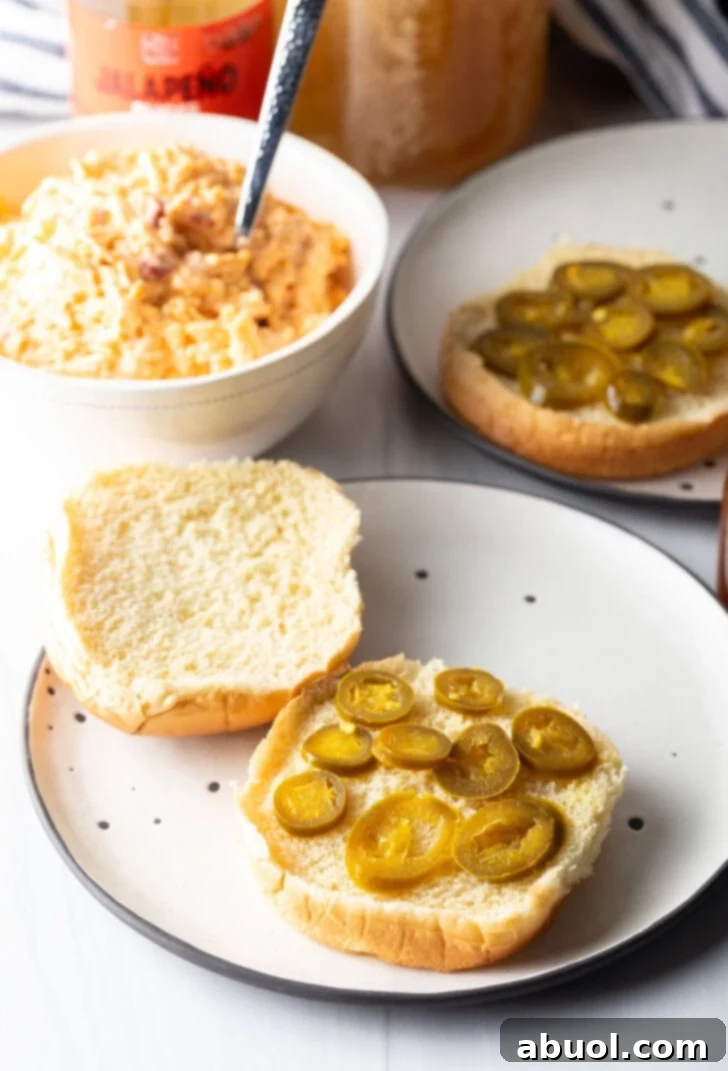 Nine vibrant green pickled jalapeño slices meticulously arranged on the bottom half of a soft burger bun, forming the spicy base for the sandwich.