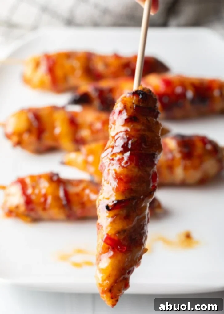 Mouthwatering Bacon-Wrapped Chicken 11 1 bacon wrapped hot sauce coated chicken skewer held up vertically to camera.