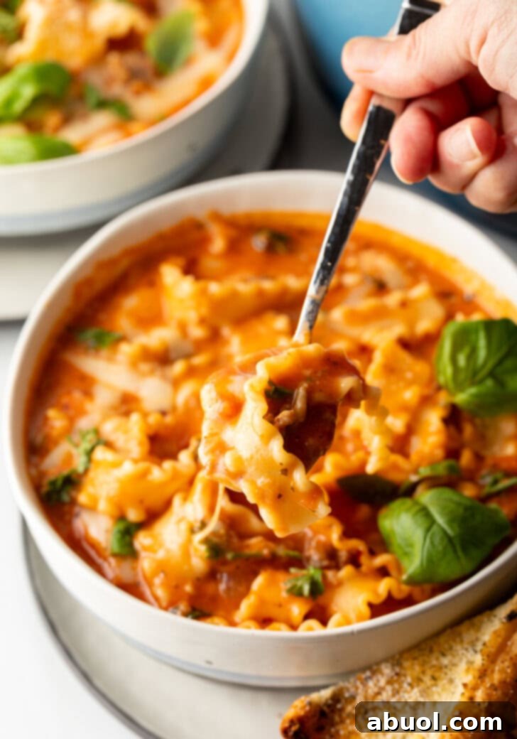 No-Fuss Lasagna Soup 8 Spoon scooping a bite of tomato cheesy soup with pasta and sausage.