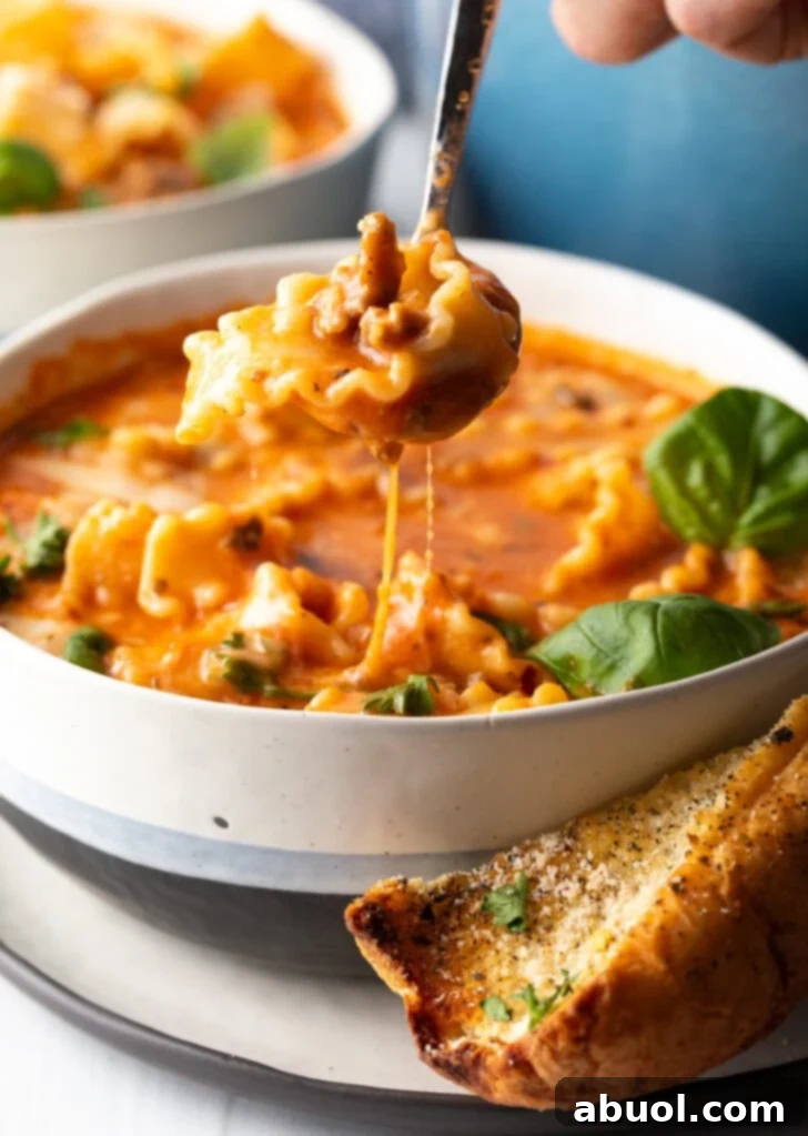 No-Fuss Lasagna Soup 4 Spoon scooping a bite of tomato cheesy soup with pasta and sausage.