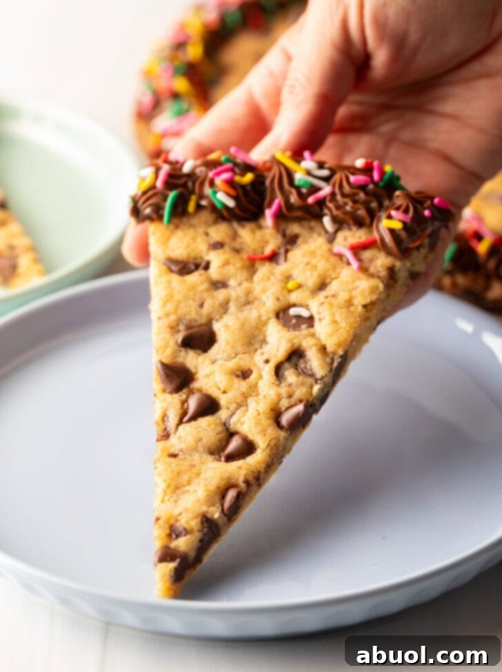 A delightful triangle slice of homemade cookie cake, perfectly cut and served on a charming pastel blue plate, inviting you to take a bite.