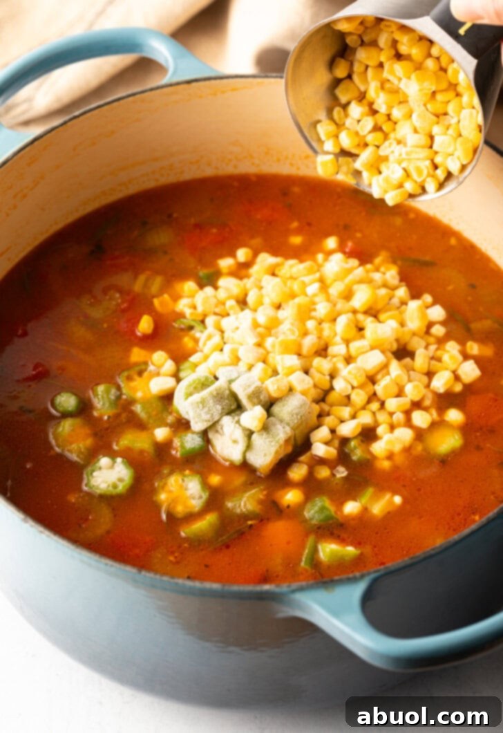 Adding canned corn to the tomato broth based soup.