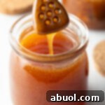 Sweet Heat Honey Blend 13 Jar of homemade Mike's hot honey with a wooden honey spatula showing a scoop of honey to camera.