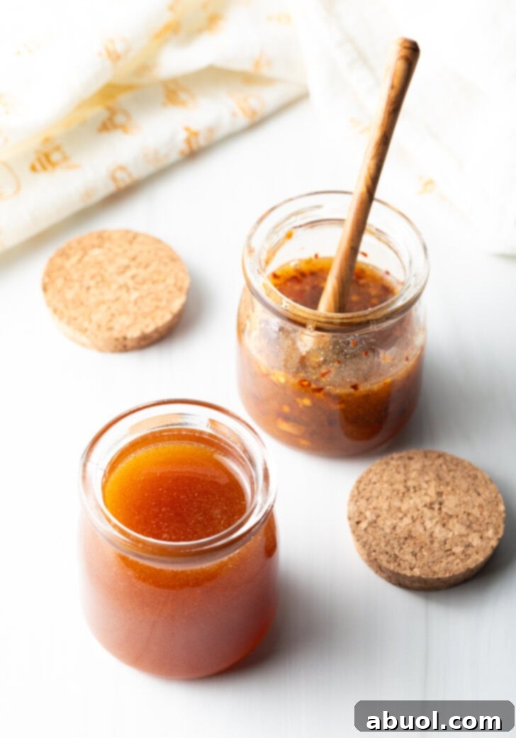 Sweet Heat Honey Blend 3 Two open small glass jars of hot honey. A wood honey spoon is in the far jar to the right.