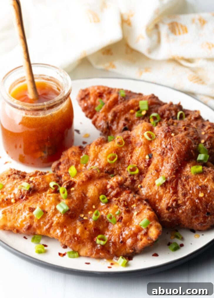 Sweet Heat Honey Blend 4 Plate of chicken tenders with small glass jar of hot honey to the side, with a wooden honey spoon in the jar.
