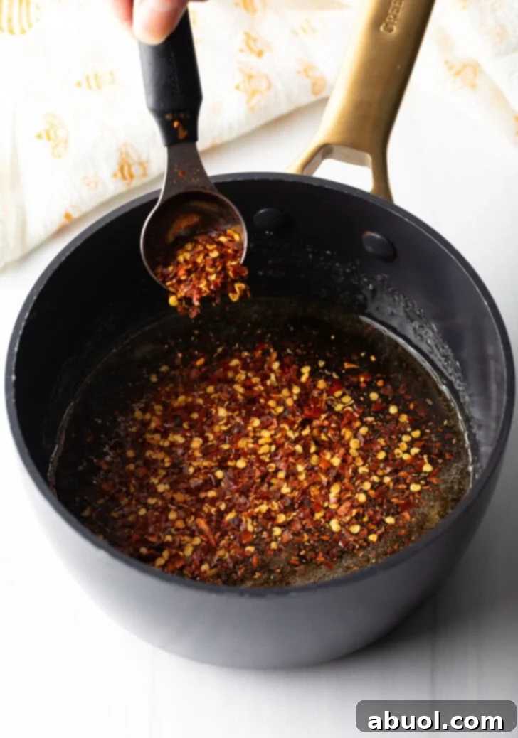 Sweet Heat Honey Blend 6 Spoon showing a spoonful of hot honey from a black cooking pot to camera.