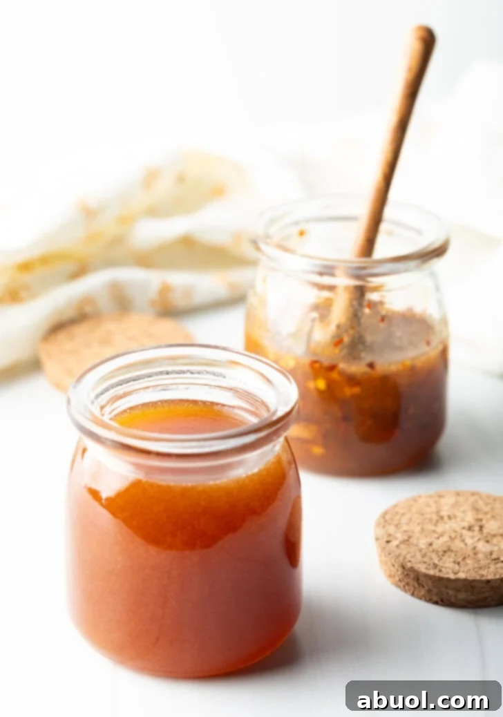 Sweet Heat Honey Blend 9 Two open small glass jars of hot honey. A wood honey spoon is in the far jar to the right.