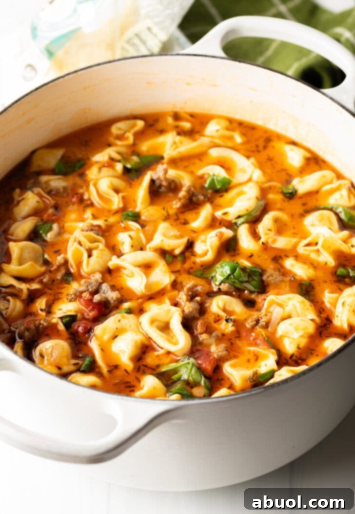 Fresh basil leaves, now stirred into the creamy Italian sausage tortellini soup, adding color and aroma.