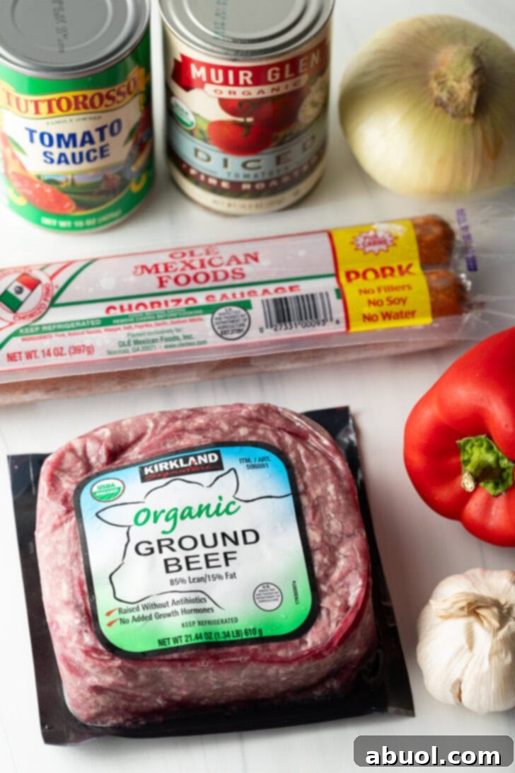 Recipe ingredients: Package of ground beef, chorizo, canned tomato sauce, canned diced tomatoes, whole red pepper, and whole bulb of garlic.