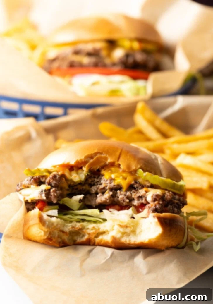 Double patty smash burger with cheese, shredded lettuce, and tomato. A large bite has been taken out to show the inside.